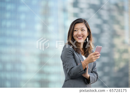 Successful businesswoman using smartphone outdoors 65728175