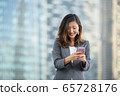 Successful businesswoman using smartphone outdoors 65728176