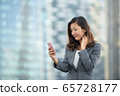 Successful businesswoman using smartphone outdoors 65728177