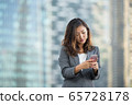 Successful businesswoman using smartphone outdoors 65728178
