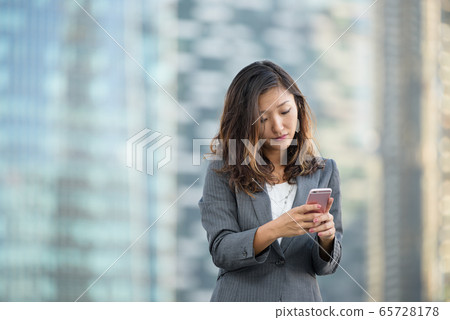 Successful businesswoman using smartphone outdoors Successful businesswoman using smartphone outdoors 65728178
