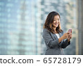 Successful businesswoman using smartphone outdoors 65728179