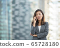 Japanese businesswoman worried look while on voice call, using smartphone, outdoors 65728180