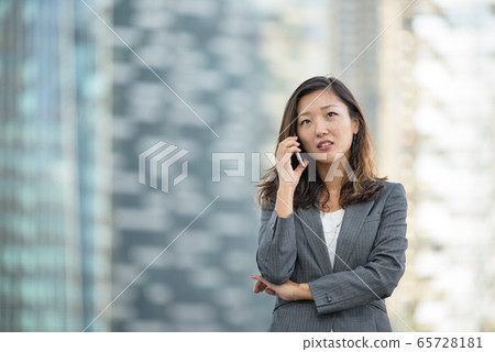 Businesswoman worried look while on voice call, using smartphone, outdoors Businesswoman worried look while on voice call, using smartphone, outdoors 65728181