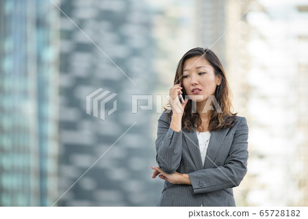 Businesswoman worried look while on voice call, using smartphone, outdoors 65728182