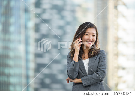 Successful businesswoman making voice call on smartphone outdoors 65728184