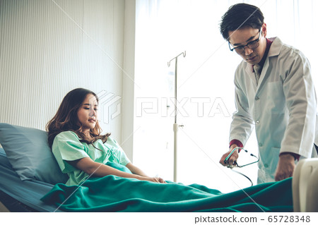 Male physician examining female patient in 65728348