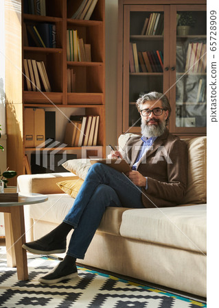 Senior successful psychologist in smart casualwear and eyeglasses making notes 65728909