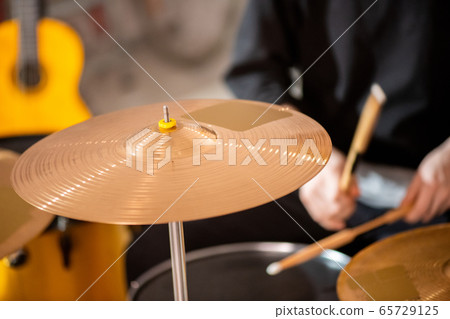 Round golden color cymbal as part of drumset on background of drummer 65729125