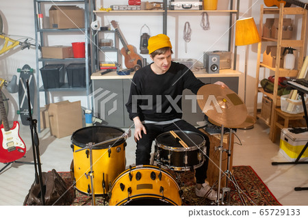 Contemporary young drummer in casualwear sitting in front of drumset Contemporary young drummer in casualwear sitting in front of drumset 65729133