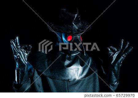Man in plague doctor costume with crow-like mask meditating isolated on black background. Creepy Man in plague doctor costume with crow-like mask meditating isolated on black background. Creepy 65729970