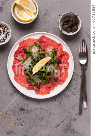 Marbled beef carpaccio with arugula, capers, lemon Marbled beef carpaccio with arugula, capers, lemon 65732654