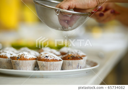 Confectioner sprinkles freshly baked muffins with Confectioner sprinkles freshly baked muffins with 65734082