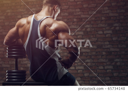 Bodybuilder strong man pumping up back muscles 65734148