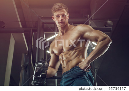 Bodybuilder drinking water after fitness workout. 65734157