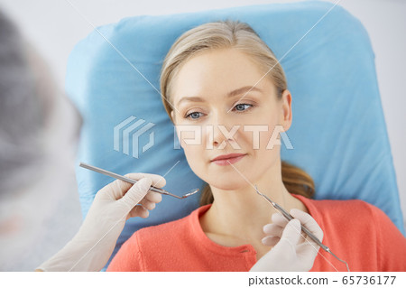 Smiling caucasian woman is being examined by dentist at dental clinic. Healthy teeth and medicine, stomatology concept Smiling caucasian woman is being examined by dentist at dental clinic. Healthy teeth and medicine, stomatology concept 65736177