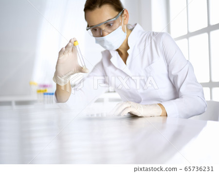 Female laboratory assistant analyzing a blood sample at hospital. Medicine, health care and researching concept 65736231