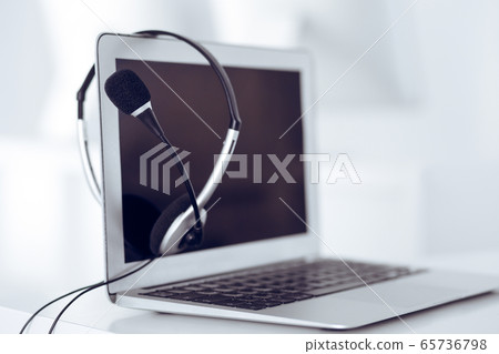 Call center and communication support, customer service help desk. VOIP headset on laptop computer Call center and communication support, customer service help desk. VOIP headset on laptop computer 65736798