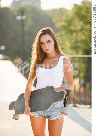 Beautiful girl with skateboard in the hands against the wall Beautiful girl with skateboard in the hands against the wall 65739099