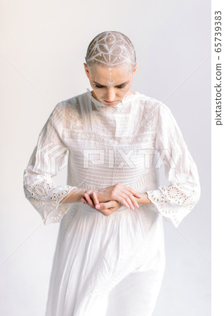 Woman in white bowing head and folding arms Woman in white bowing head and folding arms 65739383