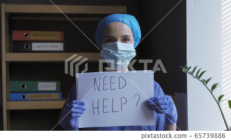 Need help question from a medical professional. Nurse in a protective mask and uniform holds a slogan on a white sheet while looking at the camera. Healthcare concept Need help question from a medical professional. Nurse in a protective mask and uniform holds a slogan on a white sheet while looking at the camera. Healthcare concept 65739886
