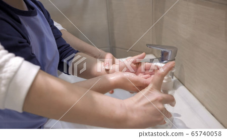 Mom clicks on a dispenser of a bottle with antibacterial soap helping her son wash his hands after shopping. Hygiene concept 65740058