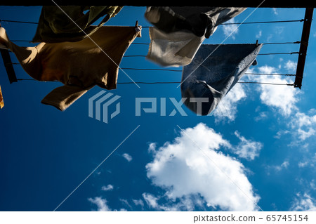 clothes are dried on the wind on background blue sky and clouds. clothes are dried on the wind on background blue sky and clouds. 65745154