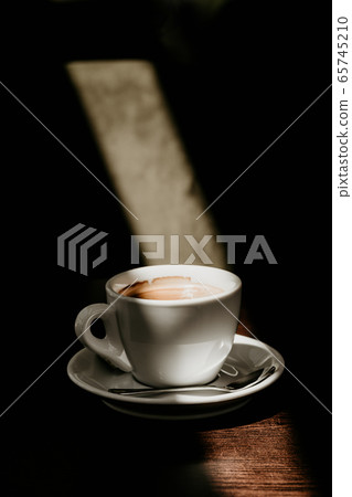 White cup of coffee on a wooden table in the sun close up White cup of coffee on a wooden table in the sun close up 65745210