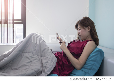 Portrait of beautiful asian woman on bed while use Portrait of beautiful asian woman on bed while use 65746406
