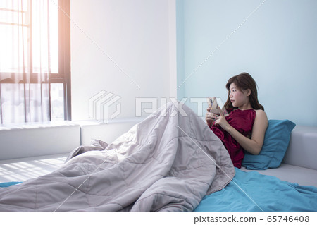 Portrait of beautiful asian woman on bed while use Portrait of beautiful asian woman on bed while use 65746408