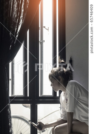 Woman Sitting At Home Using Mobile Phone Woman Sitting At Home Using Mobile Phone 65746409