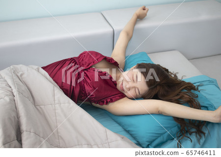 Asian woman stretching in bed after wake up in Asian woman stretching in bed after wake up in 65746411