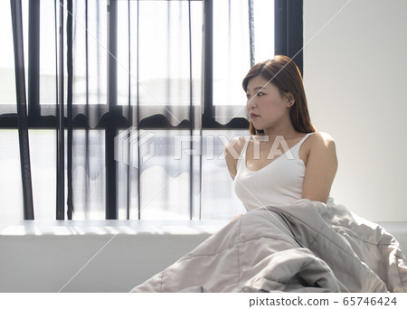 young woman sitting in bed and looks away young woman sitting in bed and looks away 65746424