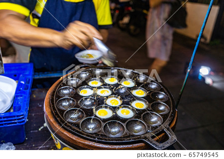 Traditional Thai Street Fast Food, quail eggs cooked in heating mantle hot indented frying pan. Asian Cuisine, Delicacy, Culture, Cooking, Snack Food, Indulgence, Nutrition and Gourmet concept. 65749545