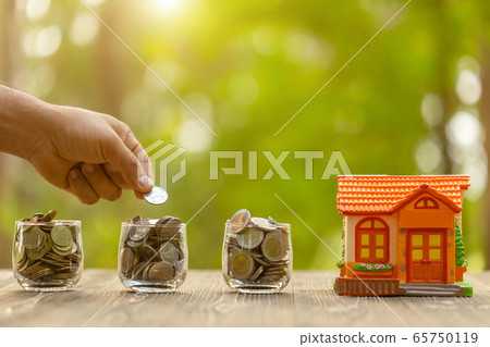 Hand put the coin to piggy bank (Home Model) on 65750119