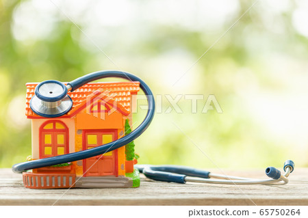 Hand holding blue stethoscope and orange house 65750264