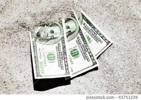 Money dolars half covered with sand lie on beach close-up. 65751239