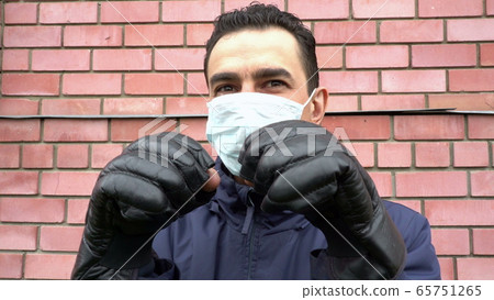 Masked man wearing boxing gloves, getting crazy, trying to protect himself from invisible threat Masked man wearing boxing gloves, getting crazy, trying to protect himself from invisible threat 65751265