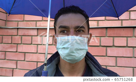 Sad man in mask standing alone under the umbrella, social distance, self isolation, quarantine Sad man in mask standing alone under the umbrella, social distance, self isolation, quarantine 65751268
