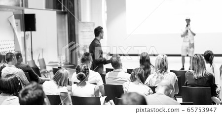Businessman in audience standing and asking question to speeker at business conference. 65753947