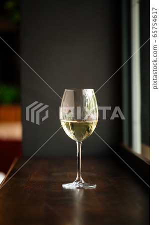 Elegant glass of white wine on wooden bar counter Elegant glass of white wine on wooden bar counter 65754617