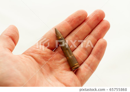 man holds a bullet for assault rifle in his hand 65755868