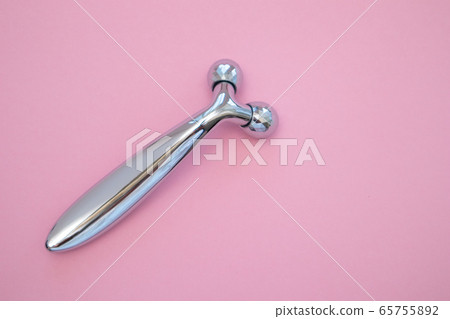 Y-shaped ball roller for face massage on pink background. Facial massager, anti-aging. 65755892