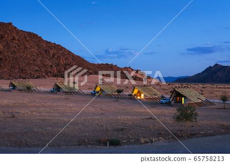 Evening at small chalets of a desert lodge near Sossusvlei in Namibia Evening at small chalets of a desert lodge near Sossusvlei in Namibia 65758213