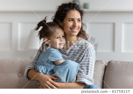 Smiling mother hugging little daughter, looking to aside, dreaming 65759137