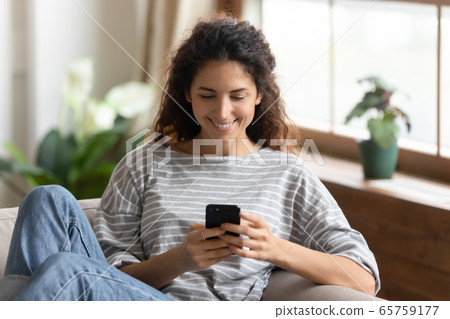 Close up smiling young woman looking at smartphone screen 65759177