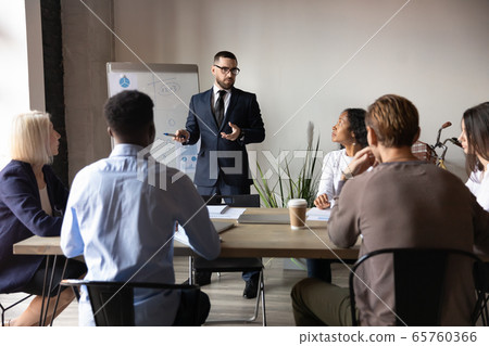 Confident businessman giving flip chart presentation at corporate meeting Confident businessman giving flip chart presentation at corporate meeting 65760366