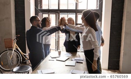 Excited diverse business people giving high five at corporate meeting 65760569