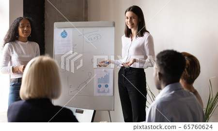 Two diverse business coaches giving flip chart presentation at meeting 65760624