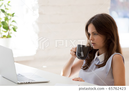 Tired woman worker look at laptop lacking work motivation Tired woman worker look at laptop lacking work motivation 65762423